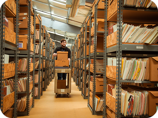 A man with glasses wheels a cart through Relay's document solutions center.