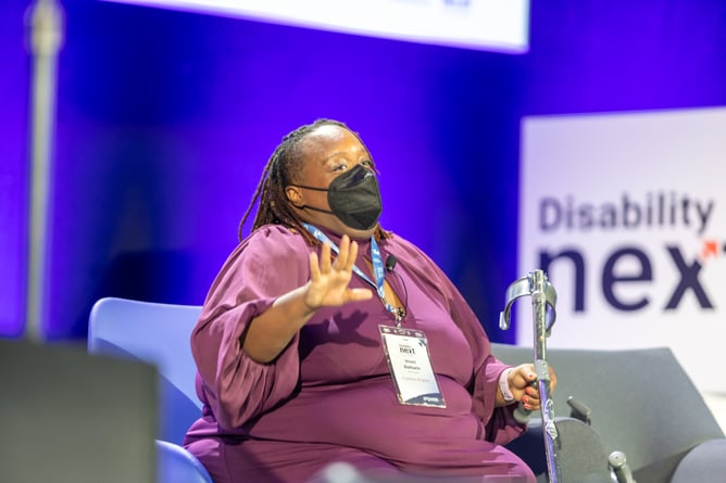 Imani Barbarin, wearing a purple blouse and a black mask, gives the opening keynote