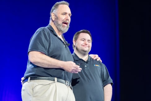 FAther and Son Duo John and Mark Cronin present at Disability NExt. Both are wearing black polos and khakis. 