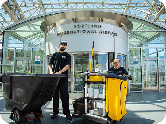 Two Relay janitors stand in front of the PDX airport. 