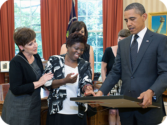President Barack Obama looks at a framed painting presented to him by artist and disability rights advocate Lois Curtis in the Oval Office.