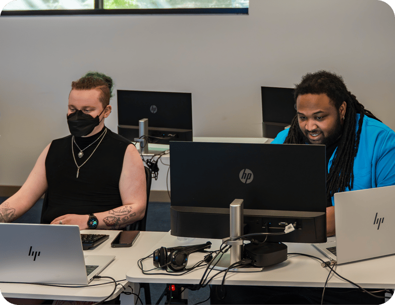 Two abilIT students working at computer stations in a classroom